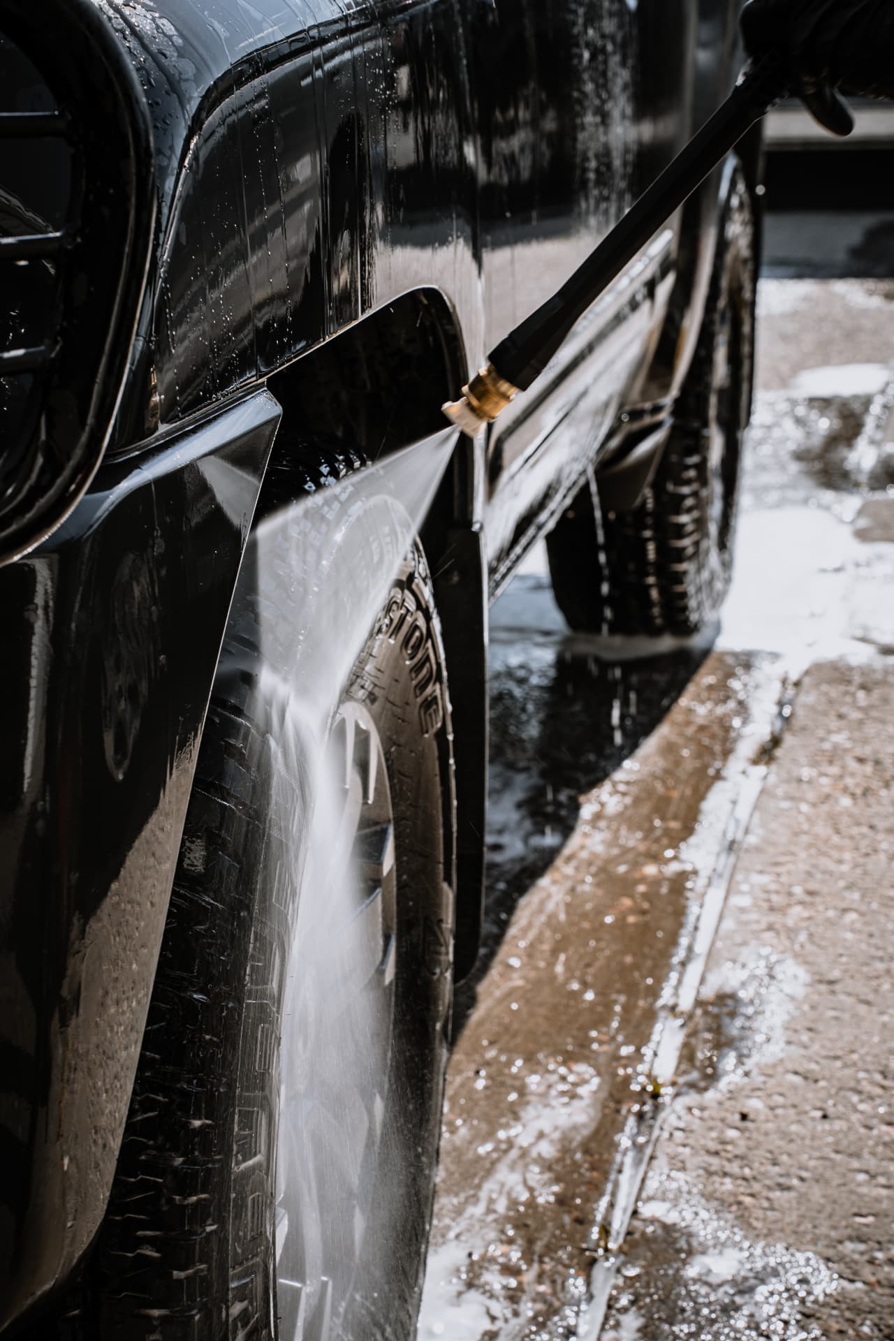 Pressure rinsing soap off the side of a black pickup truck